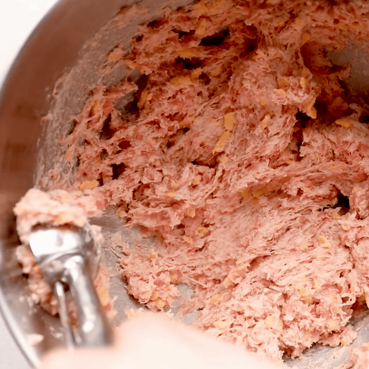 overhead image of sausage ball ingredients being mixed in mixer and then removed with scoop